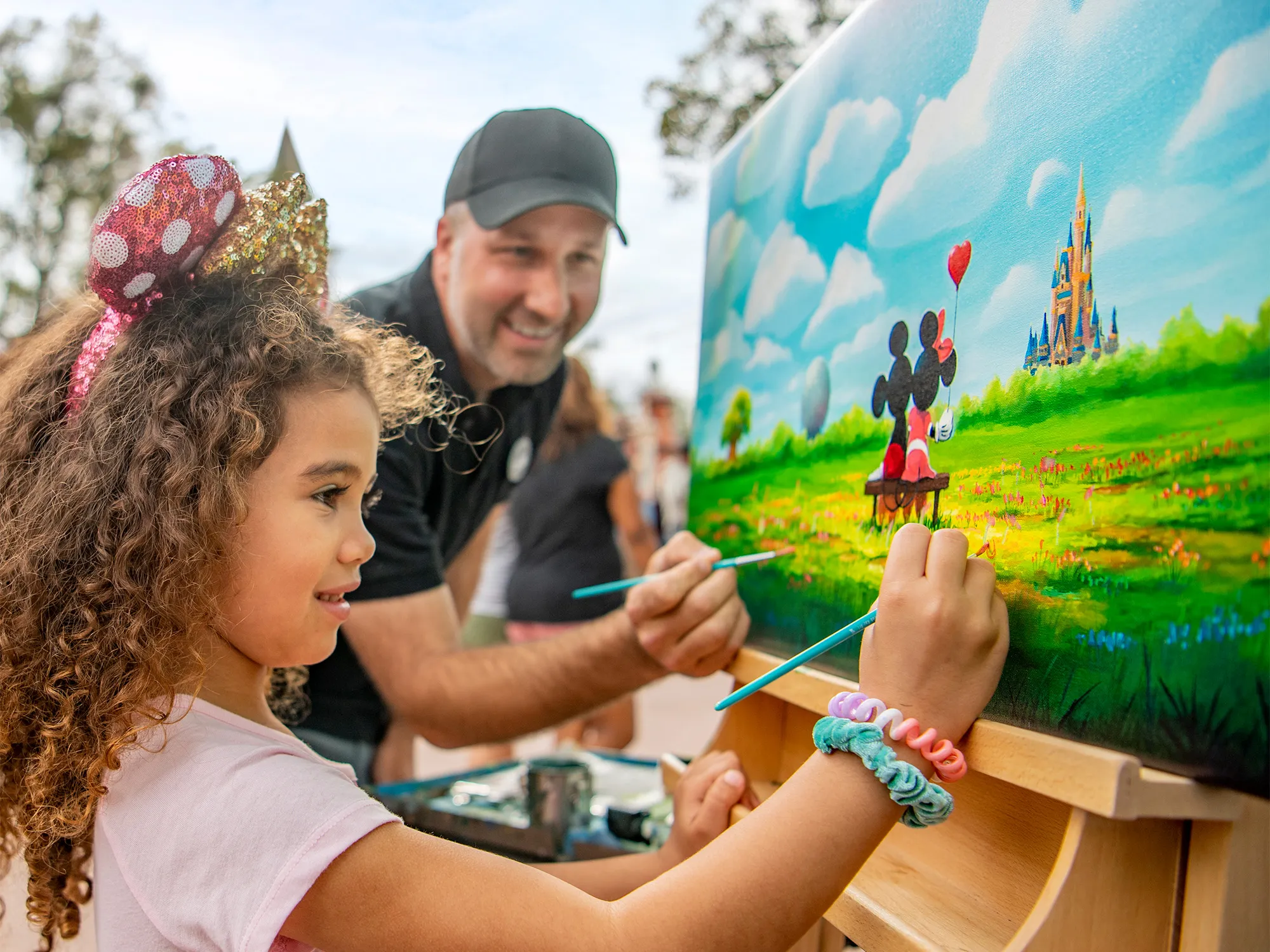 Child painting at an outdoor easel during a Disney park activity