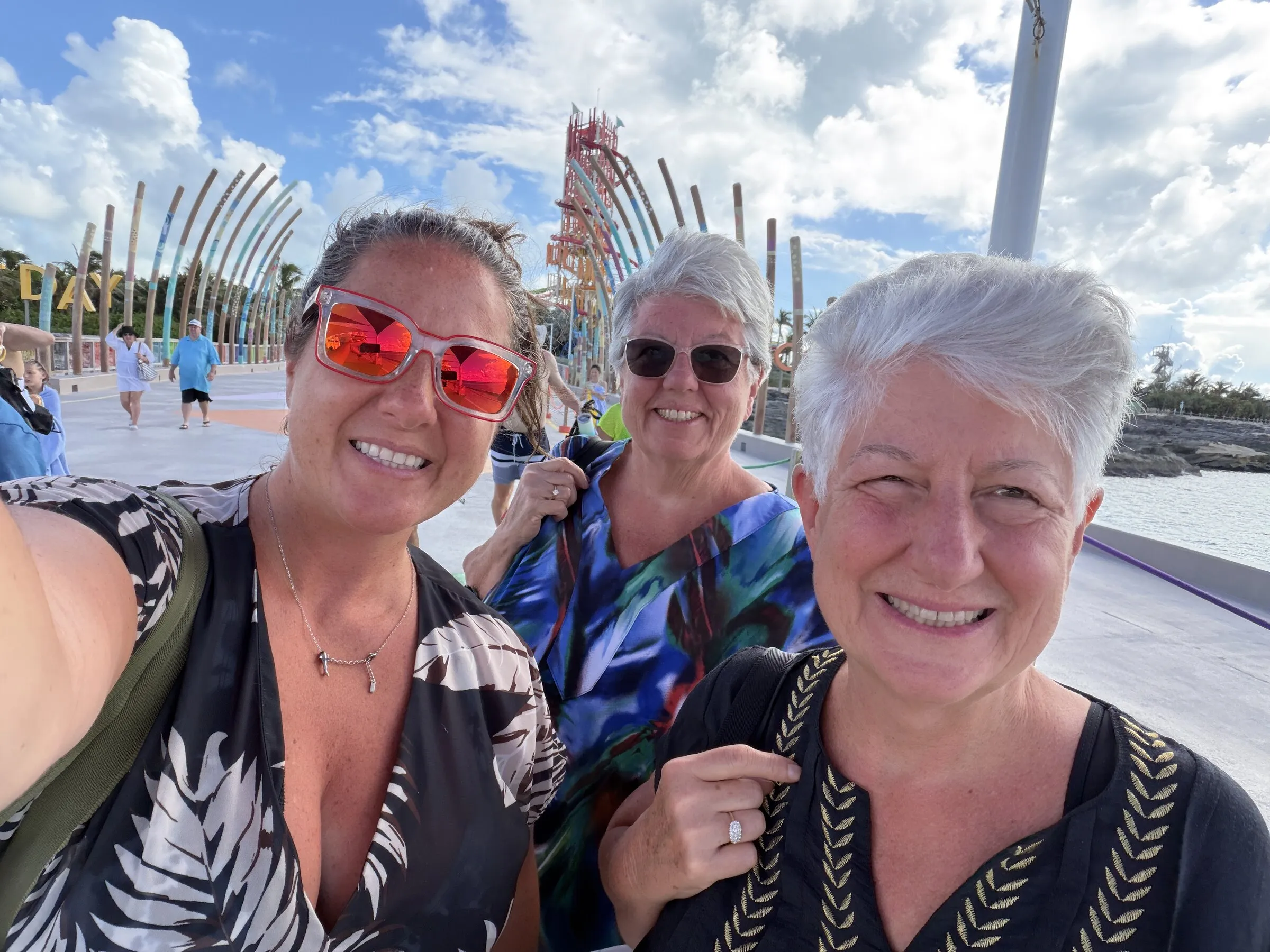Jenn and two travel companions smiling at a cruise port at golden hour